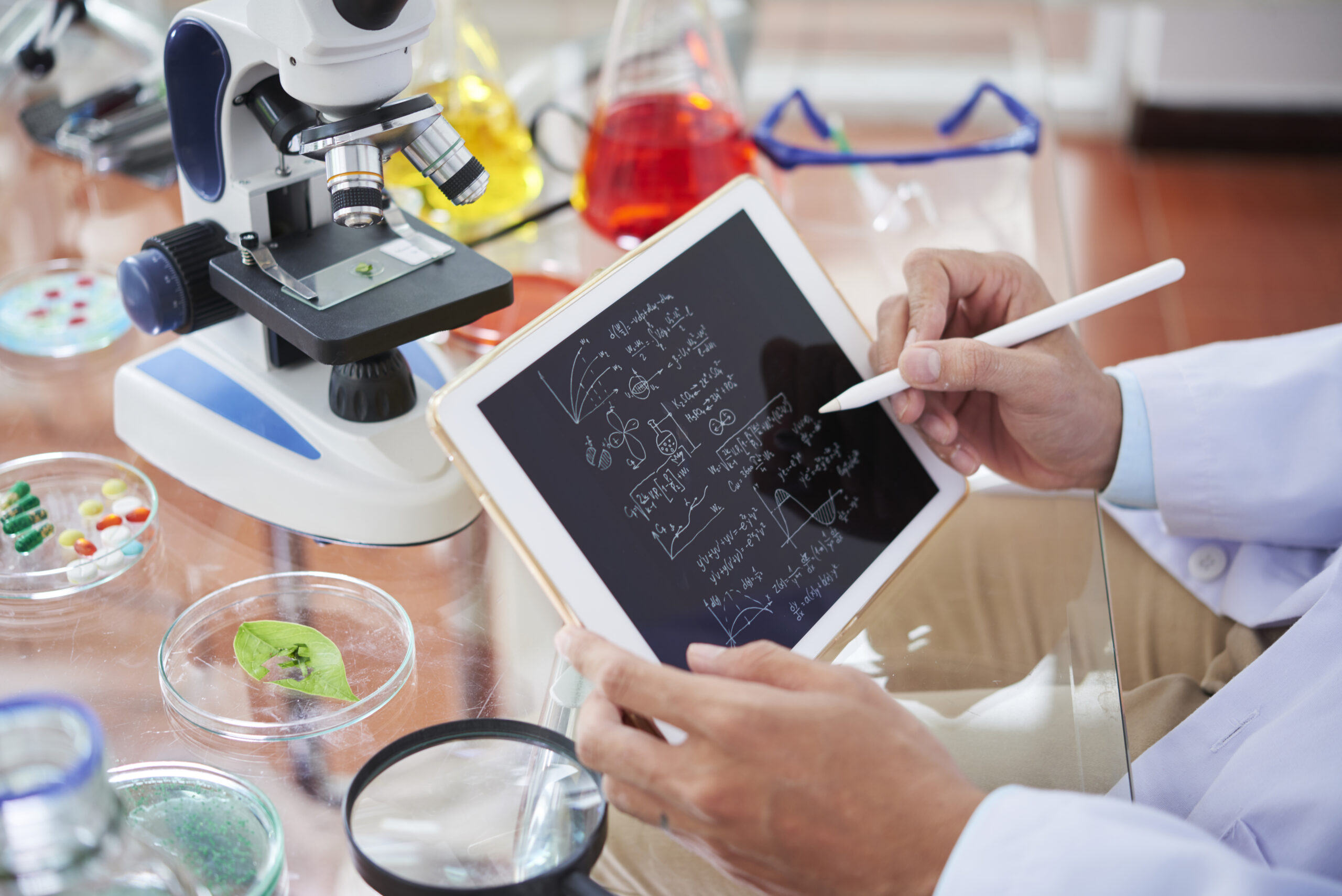 Scientist drawing chemical formulas and making calculations on tablet computer
